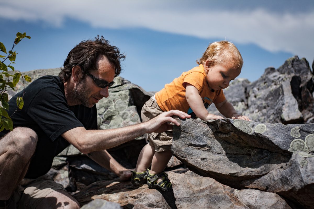 Father and young son climbing a rock pile.