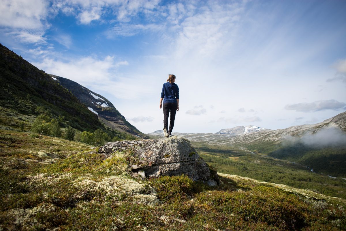 Woman stands on a rock in the mountains