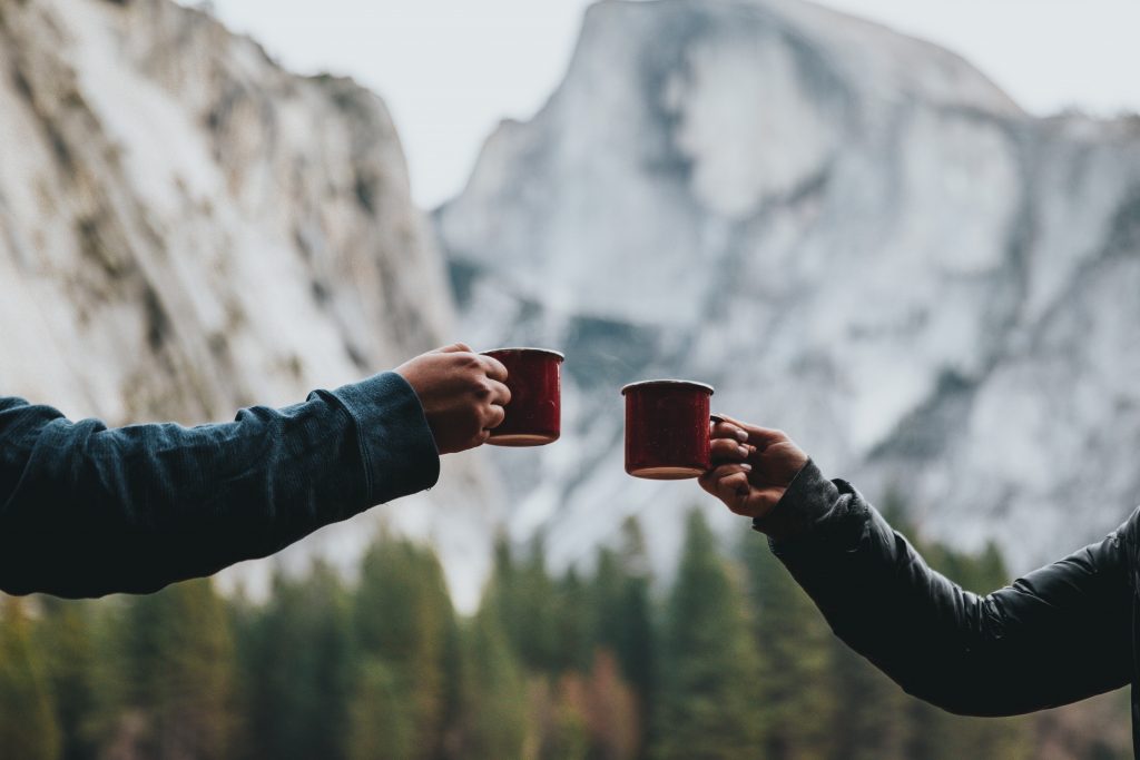 Couple holding up mugs in the mountains